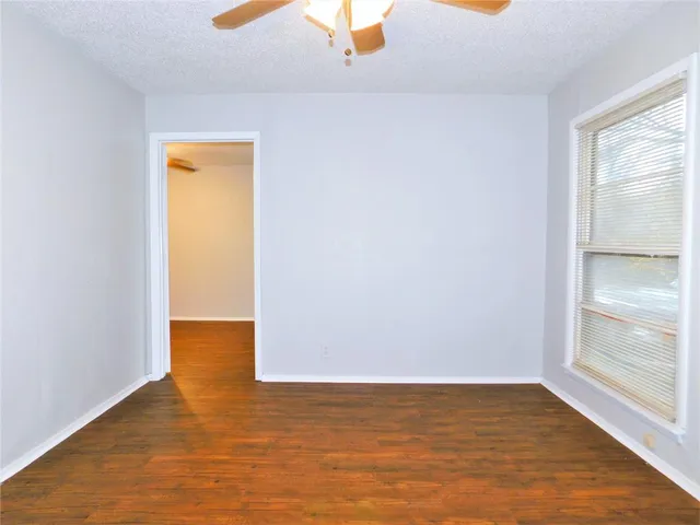 a view of an empty room with window and wooden floor