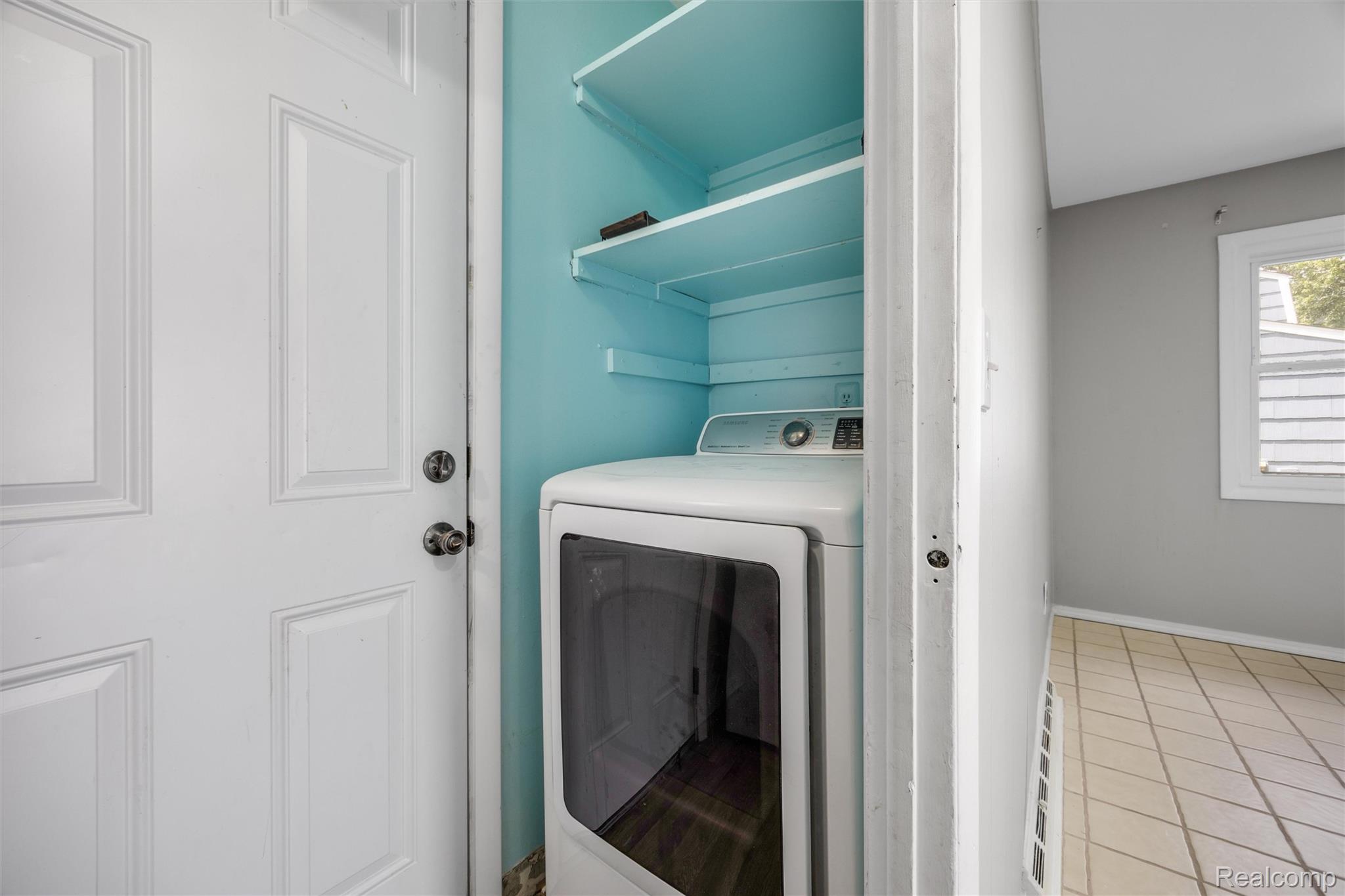 4942 Butler Drive Troy, MI 48085 - Photo 11 of 33 Dedicated laundry nook featuring a stacked washer and dryer, integrated shelving, and a bright blue interior