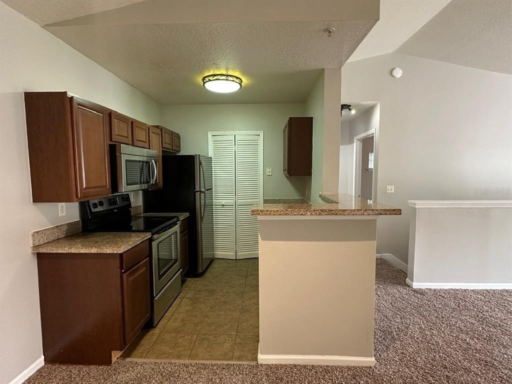4348 South Kirkman Road, Unit 812 Orlando, FL 32811 - Photo 3 of 22 a kitchen with stainless steel appliances granite countertop a refrigerator a stove and a sink