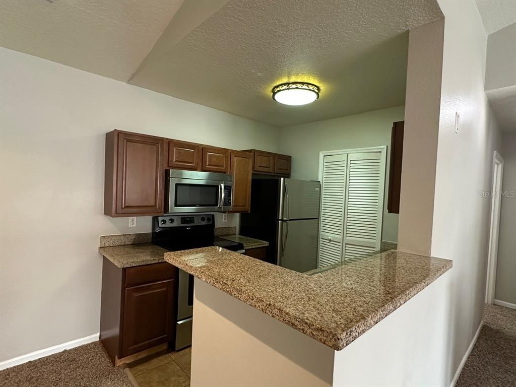 4348 South Kirkman Road, Unit 812 Orlando, FL 32811 - Photo 5 of 22 a kitchen with stainless steel appliances granite countertop a sink stove and refrigerator