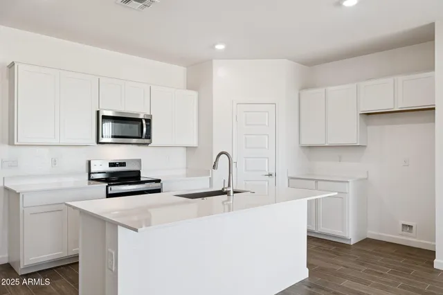 a kitchen with stainless steel appliances a sink a stove a microwave a sink a refrigerator and cabinets