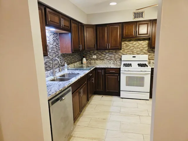 a kitchen with stainless steel appliances granite countertop a stove a sink and a refrigerator