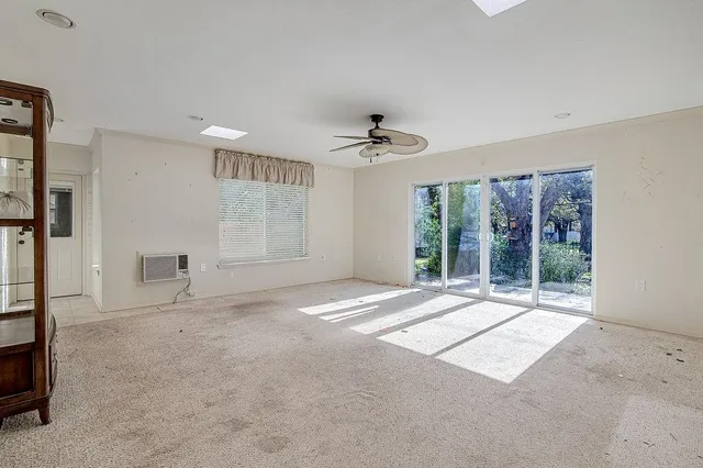 a view of an empty room with a window and a kitchen
