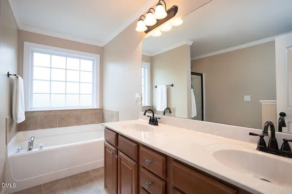 a bathroom with a tub a sink and mirror