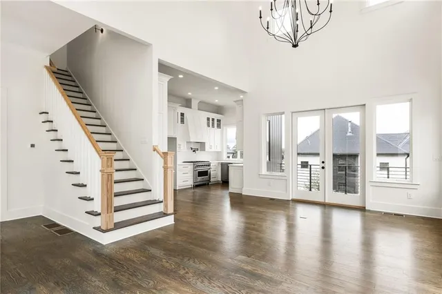 a view of an empty room with wooden floor and stairs