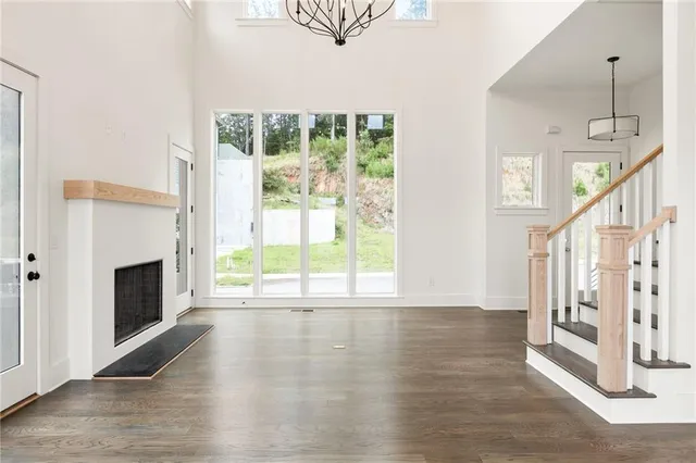 a view of an empty room with wooden floor fireplace and a window