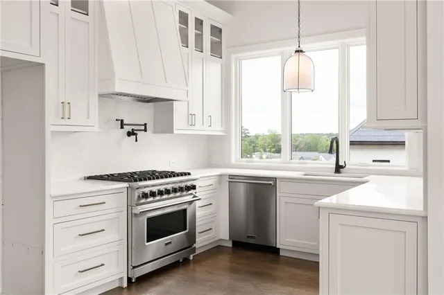 a kitchen with white cabinets appliances and window