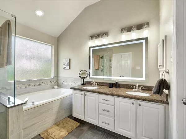 a bathroom with a double vanity sink and mirror with bathtub
