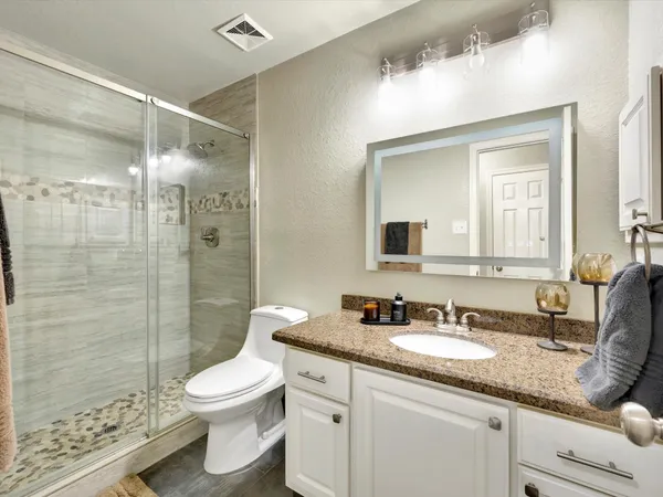 a bathroom with a granite countertop sink toilet and shower