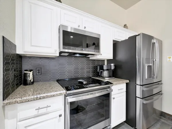 a kitchen with stainless steel appliances granite countertop a refrigerator stove and microwave