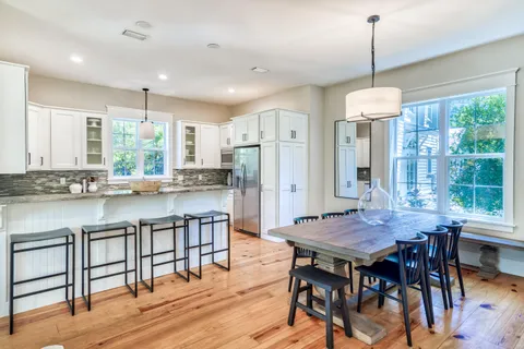 a kitchen with kitchen island a dining table chairs and white cabinets