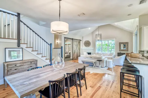 a dining room with wooden floor a chandelier a wooden table and chairs