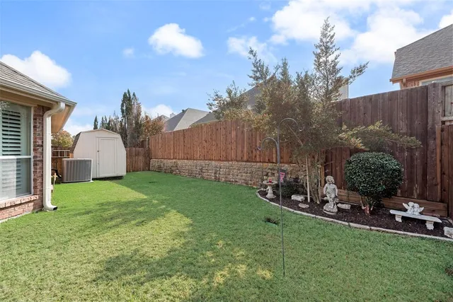 a view of a backyard with plants and a large tree