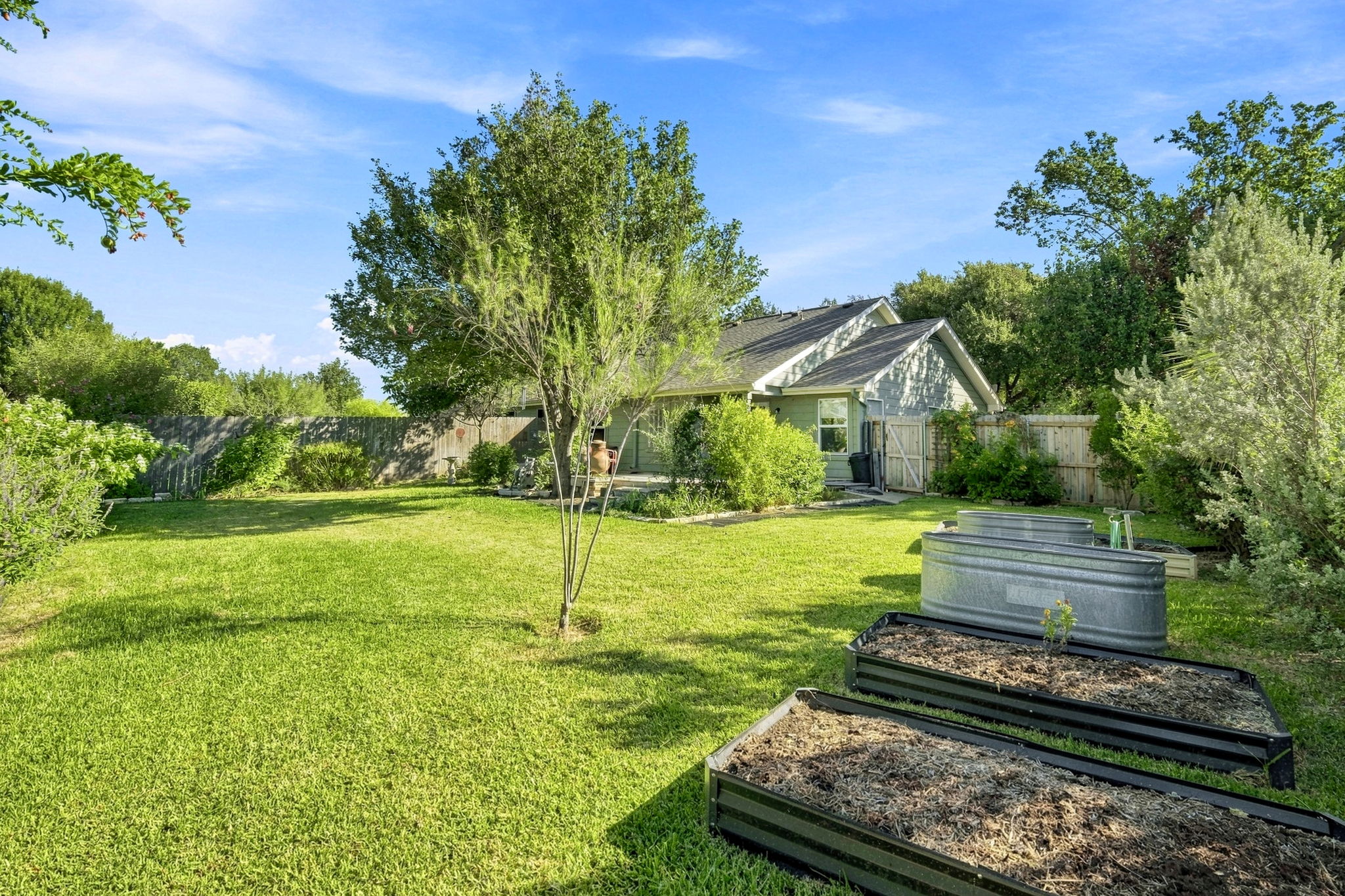 196 Prairie Springs Loop Georgetown, TX 78626 - Photo 25 of 34 Lush green grass and garden beds frame the rear exterior of this single-story home.