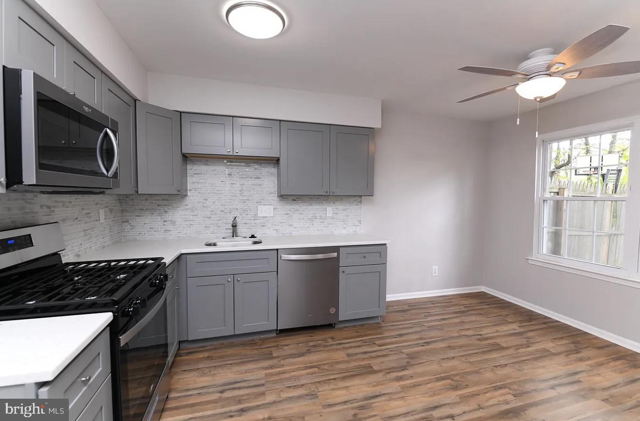 26 Hampton Gate Drive, Unit B Sicklerville, NJ 08081 - Photo 6 of 17 a kitchen with stainless steel appliances granite countertop a sink a stove a microwave oven with cabinets and wooden floor