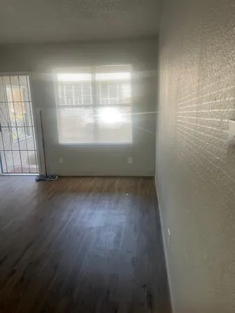 an empty room with wooden floor and windows with curtains