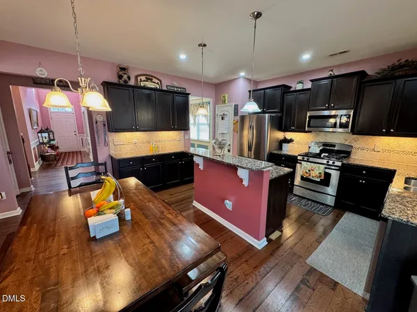 a kitchen with stainless steel appliances kitchen island granite countertop a stove a sink and a refrigerator