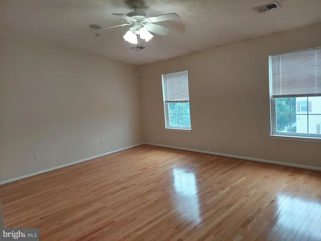 a view of an empty room with a window and wooden floor