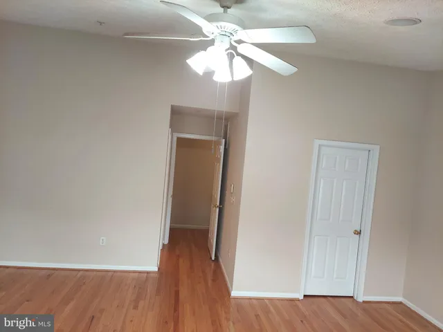 wooden floor in an empty room with a chandelier fan