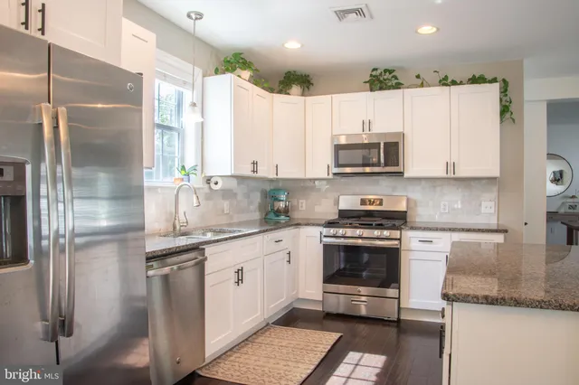 a kitchen with stainless steel appliances granite countertop a stove a sink and a refrigerator
