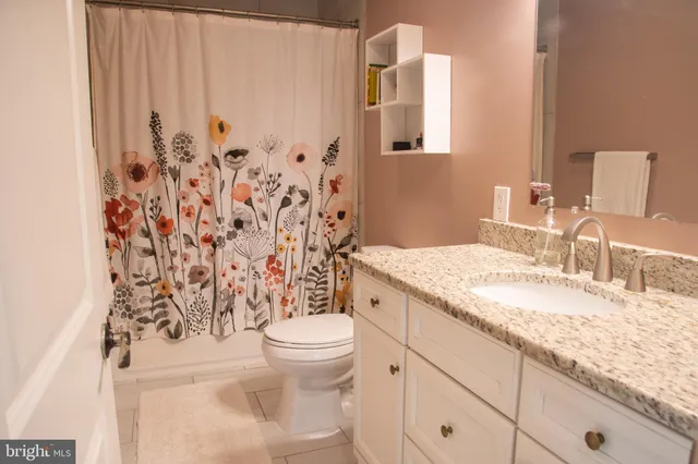a bathroom with a granite countertop sink toilet and mirror