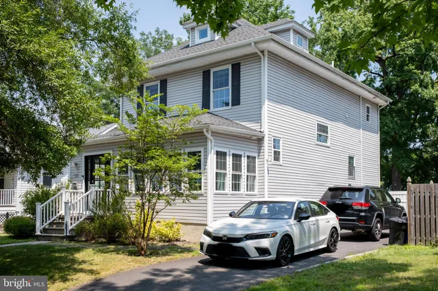a white house that has a small yard and large trees