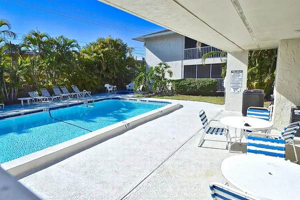 a view of a swimming pool with a lawn chairs under an umbrella