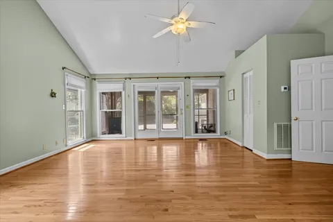 a view of an empty room with wooden floor and a window