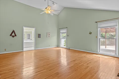 a view of empty room with wooden floor and fan