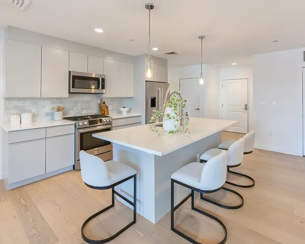 a kitchen with stainless steel appliances granite countertop a sink a stove a refrigerator a dining table and chairs