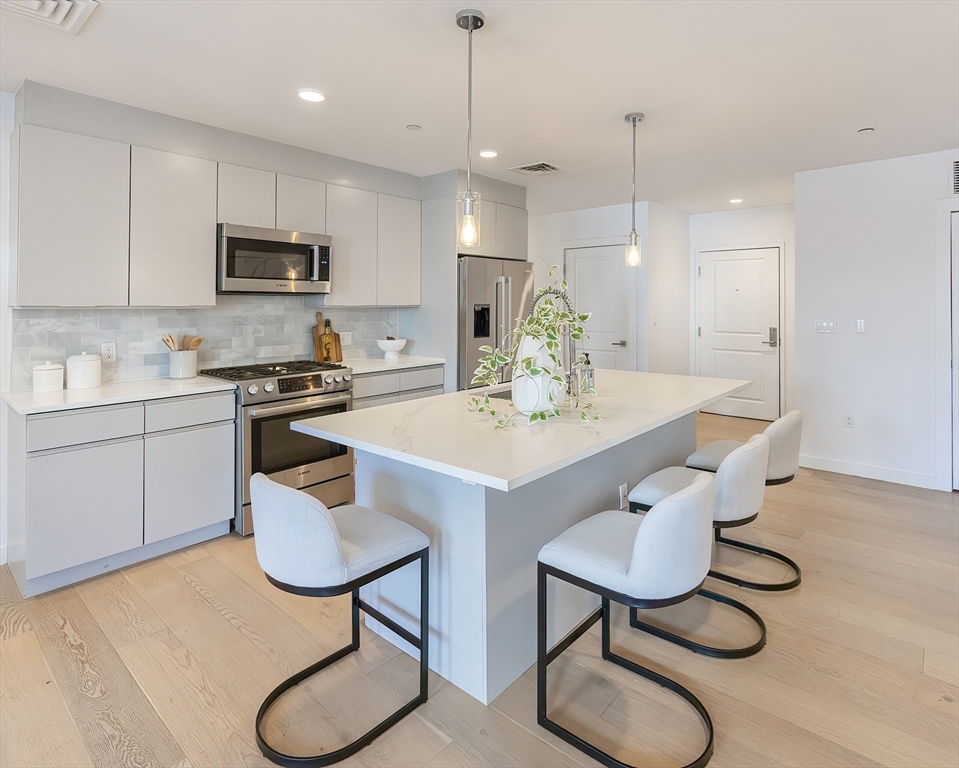 a kitchen with stainless steel appliances granite countertop a sink a stove a refrigerator a dining table and chairs