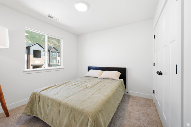 4646 Alder Drive, Unit 223 Mapleton, UT 84664 - Photo 18 of 35 Bright bedroom featuring a large window, neutral carpeting, and a white paneled door with matte black hardware