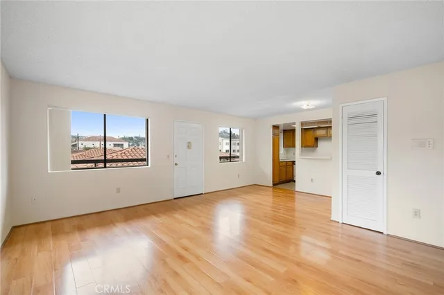 an empty room with wooden floor and windows