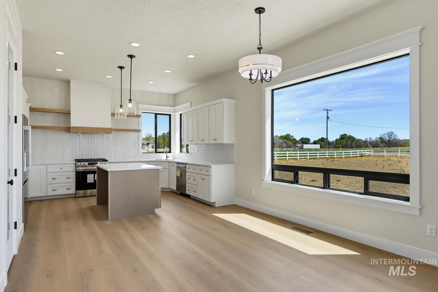5054 Heritage Drive Marsing, ID 83639 - Photo 9 of 38 Spacious open-concept kitchen featuring white cabinetry, a central island with countertop, stainless steel appliances, and light wood-finish flooring