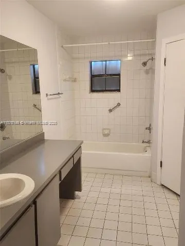 a bathroom with a granite countertop sink a toilet a mirror and bathtub