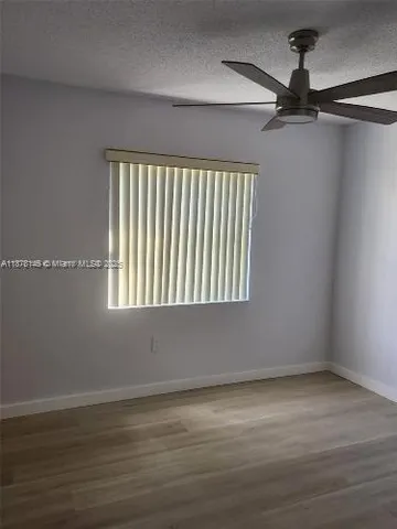 en empty room with wooden floor fan and windows