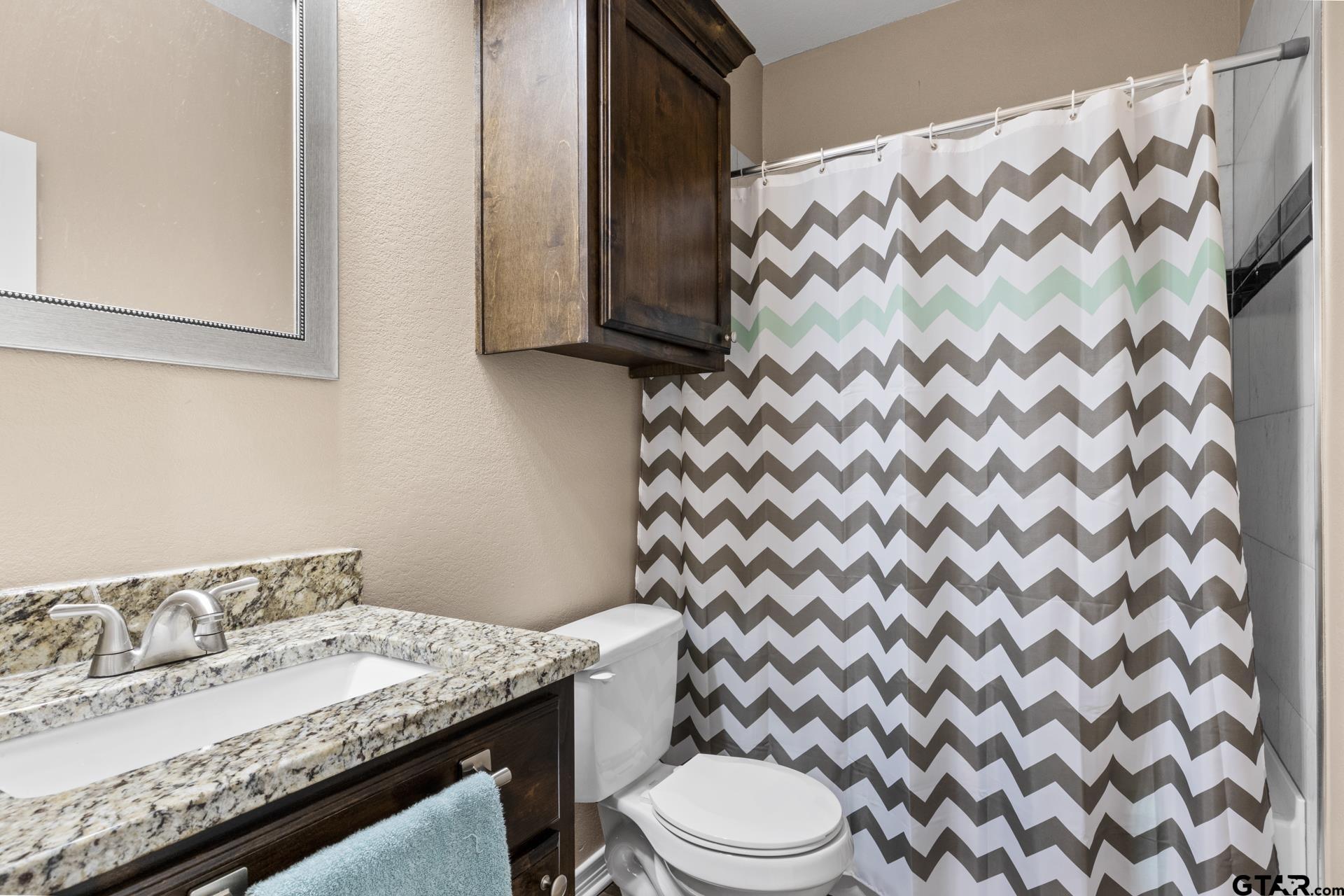 25 Private Road Pittsburg, TX 75686 - Photo 15 of 29 a bathroom with a granite countertop bathtub sink vanity mirror and toilet