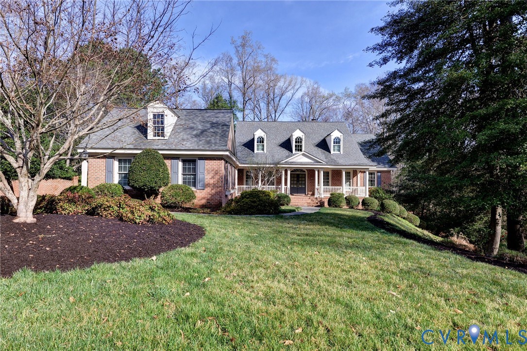 Cape cod house with a porch, brick siding, and a f
