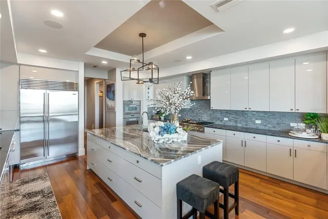 a kitchen with stainless steel appliances granite countertop a stove a refrigerator and a white cabinets