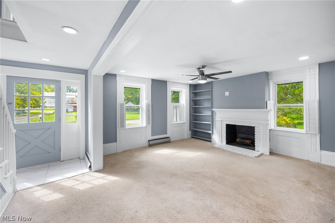 39016 Detroit Road Avon, OH 44011 - Photo 4 of 36 Unfurnished living room with light colored carpet, ceiling fan, a brick fireplace, and a baseboard radiator