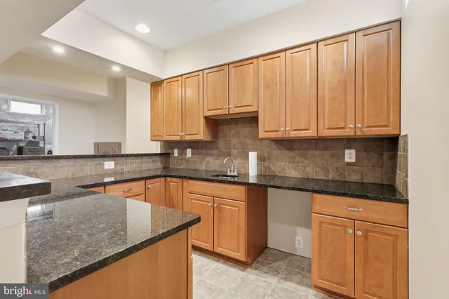 a kitchen with granite countertop a sink a stove and cabinets