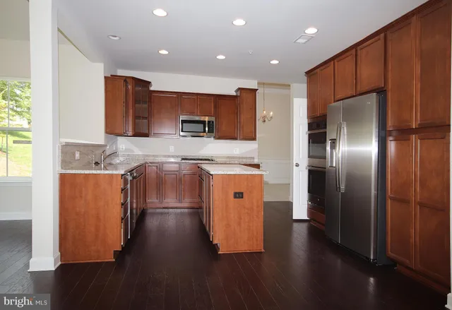 a kitchen with stainless steel appliances granite countertop a refrigerator a sink a stove and oven with wooden floor