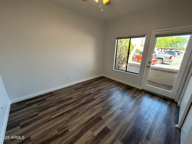 a view of an empty room with wooden floor and a window