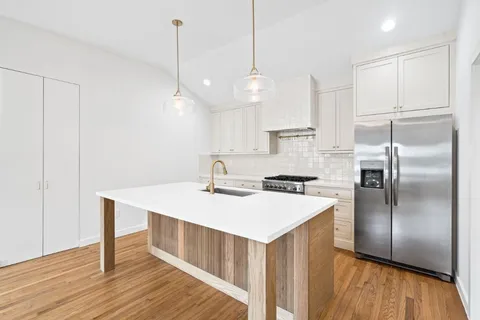 a kitchen with a refrigerator a sink and wooden floor