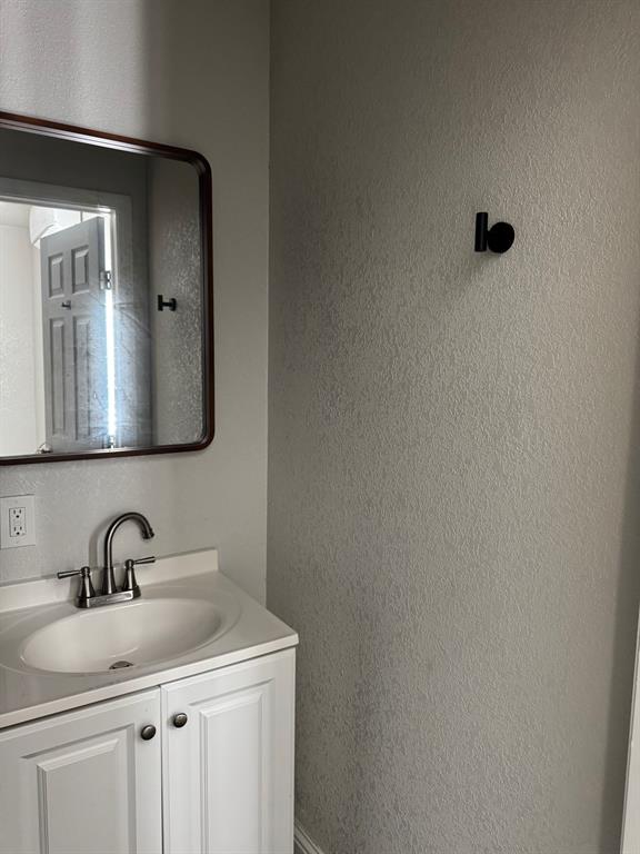 9551 Lechner Road, Unit G Fort Worth, TX 76179 - Photo 15 of 15 White vanity with a built-in sink, chrome faucet, and dark-framed mirror