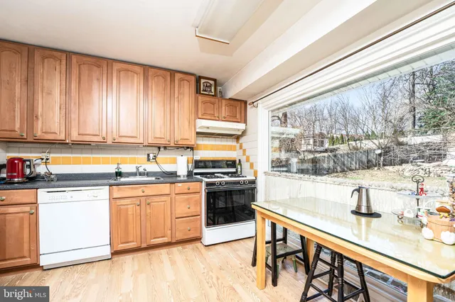 a kitchen with stainless steel appliances granite countertop a stove a sink dishwasher and cabinets with wooden floor