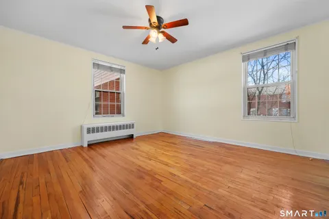 a view of an empty room with a window and wooden floor