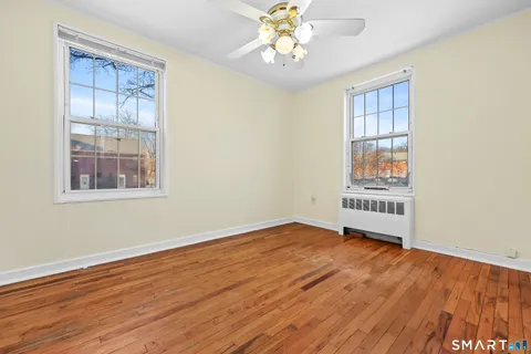 a view of an empty room with a window and wooden floor