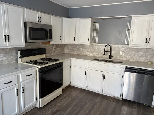 a kitchen with granite countertop a sink cabinets and stainless steel appliances