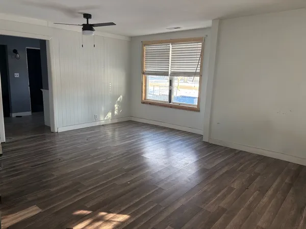 an empty room with wooden floor and windows